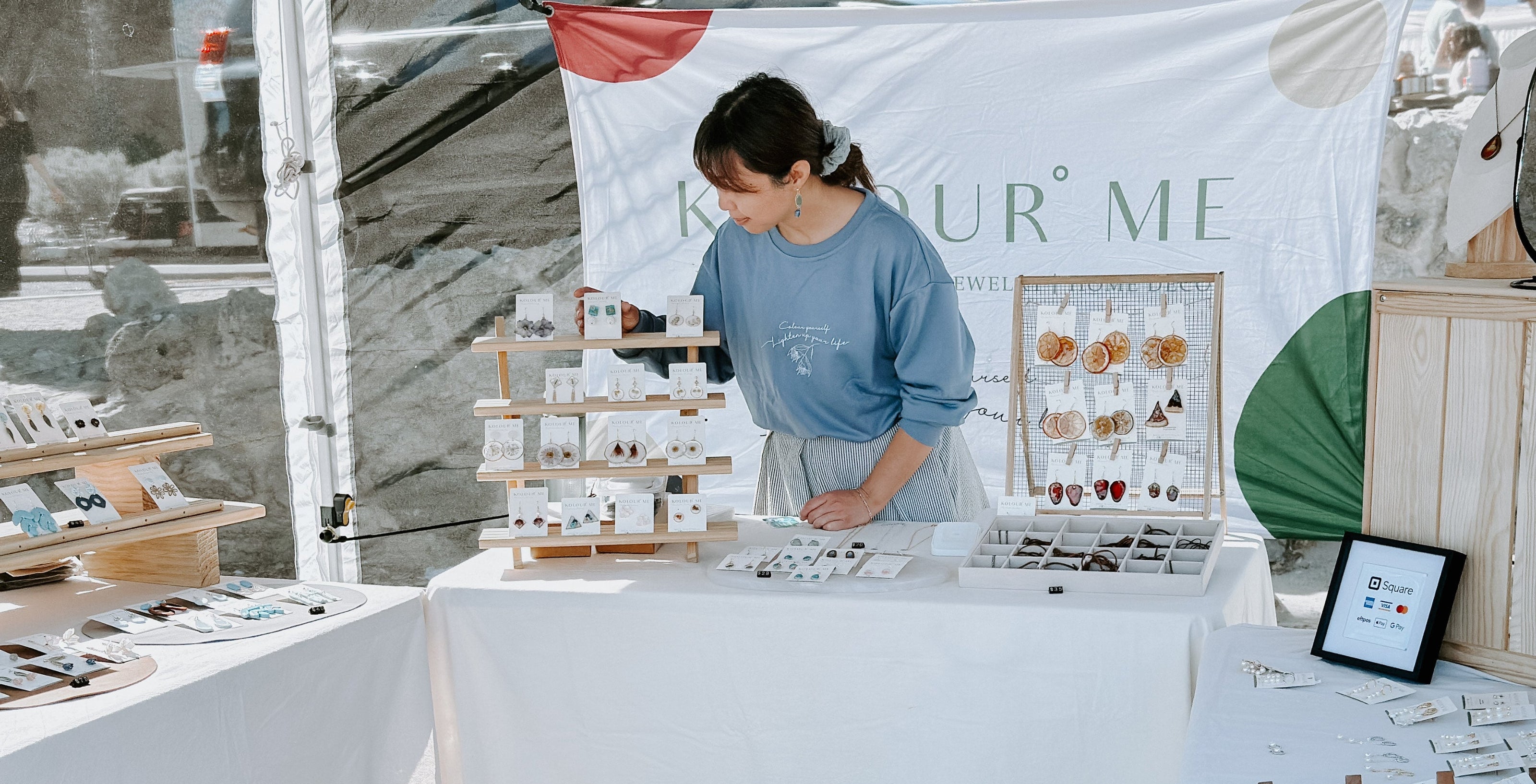 Kolour Me at a craft fair with tables displaying various items with a flower earrings, resin artwork to create wearable art jewellery in Australia.
